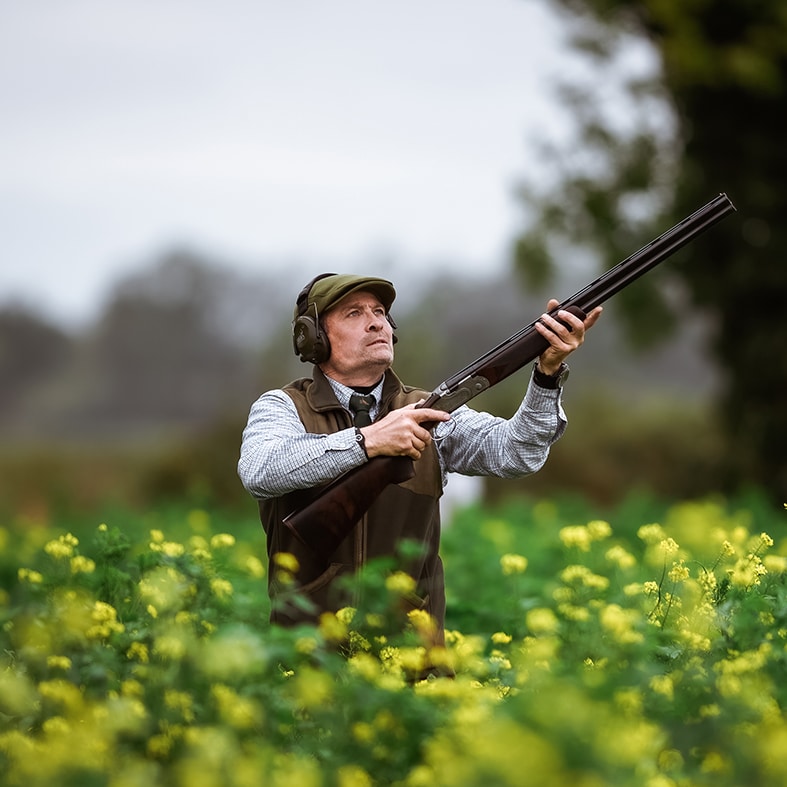 Game shooter holding a shot gun and looking into the sky