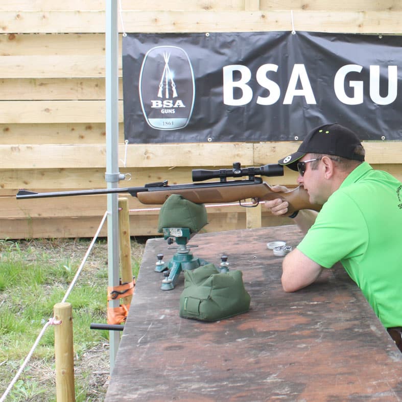 An air gunner aiming down the scope of their rifle