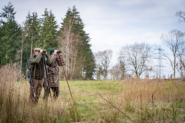 A pair of deer stalkers watching through binoculars