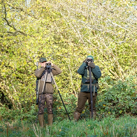 A pair of deer stalkers watching through binoculars