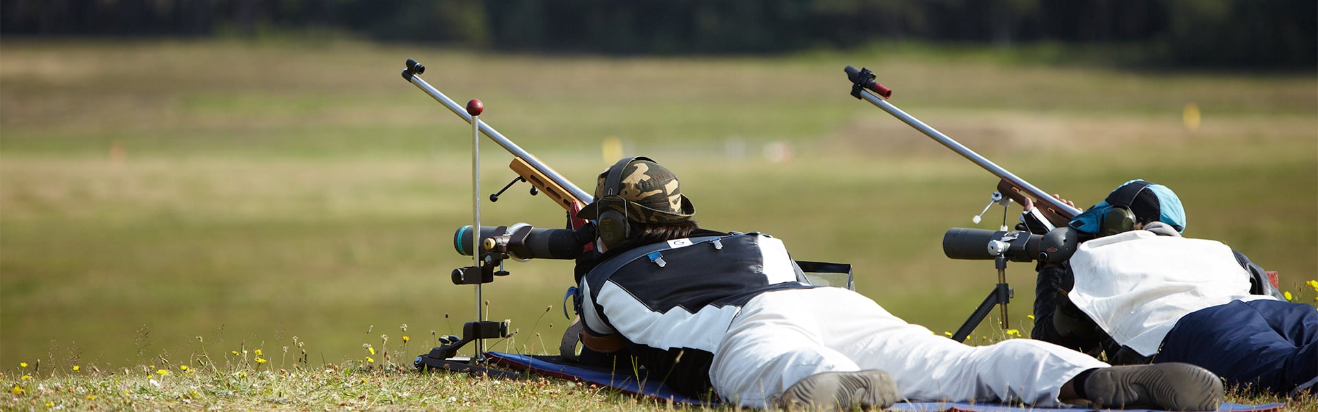 Two target shooters lying down aiming down the scopes of their rifles