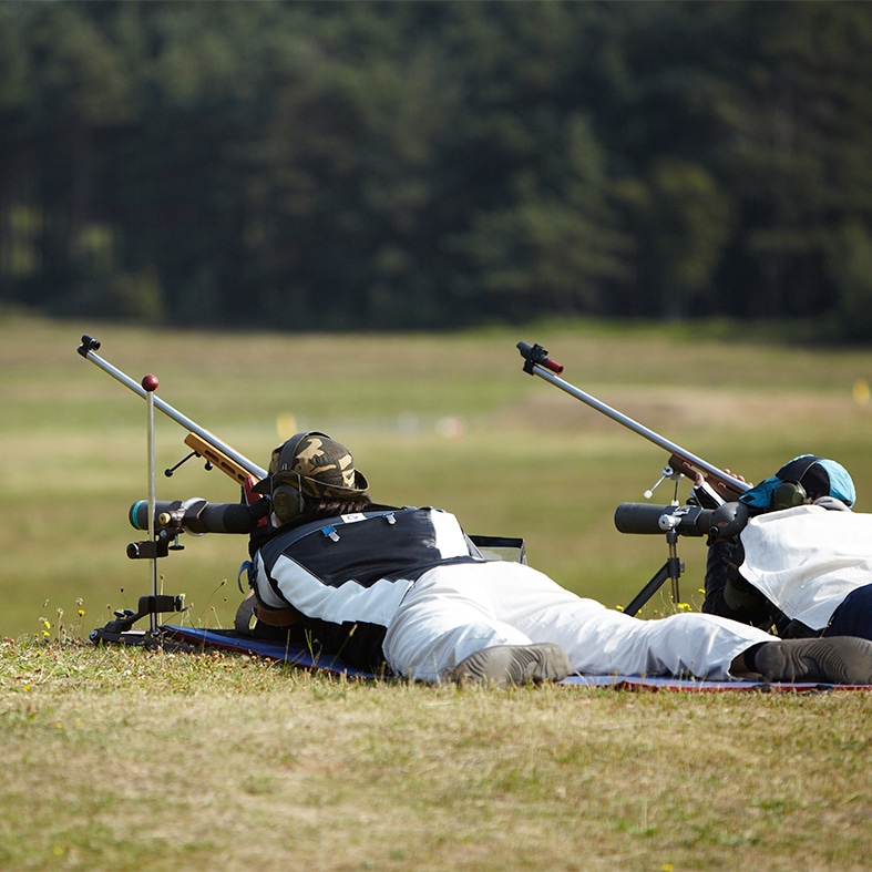 Two target shooters lying down aiming down the scopes of their rifles