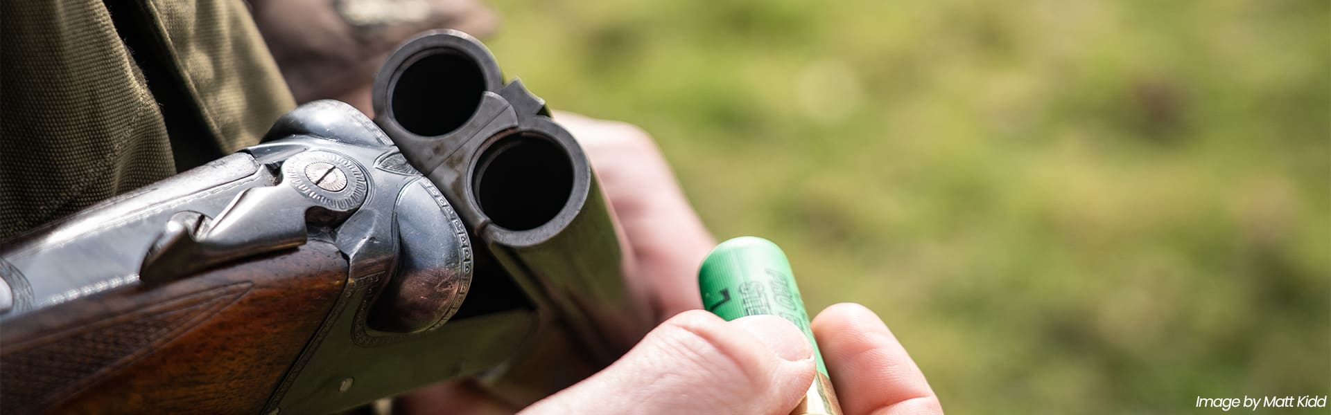 A close up of a shooter loading a shotgun