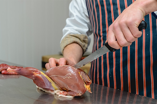 A chef preparing small game meat