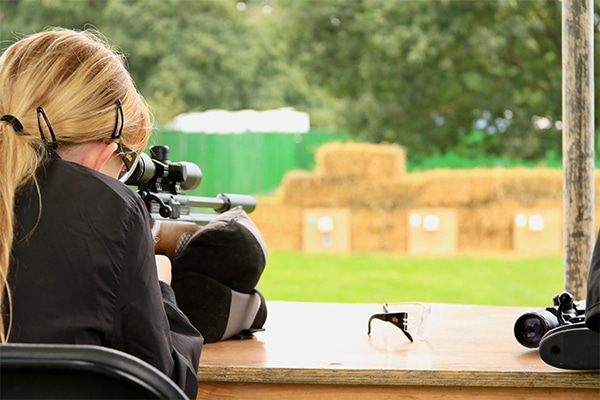 Air rifle shooter aiming down her scope