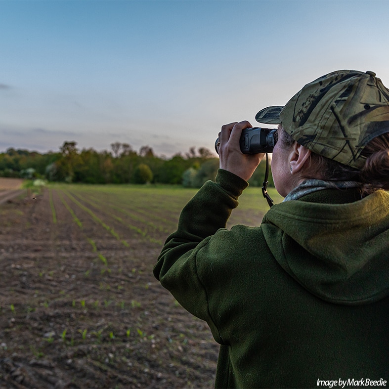 A shooter looking through binoculars