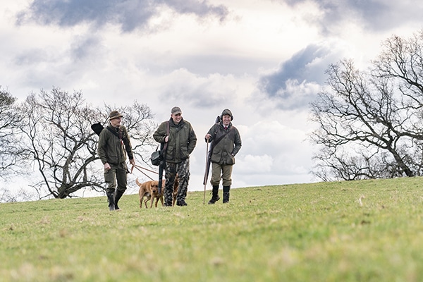 Game shooters walking in a field