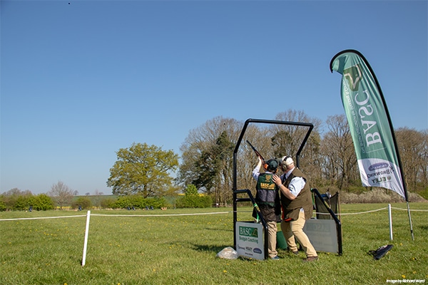 A BAC coach with a student firing a shotgun
