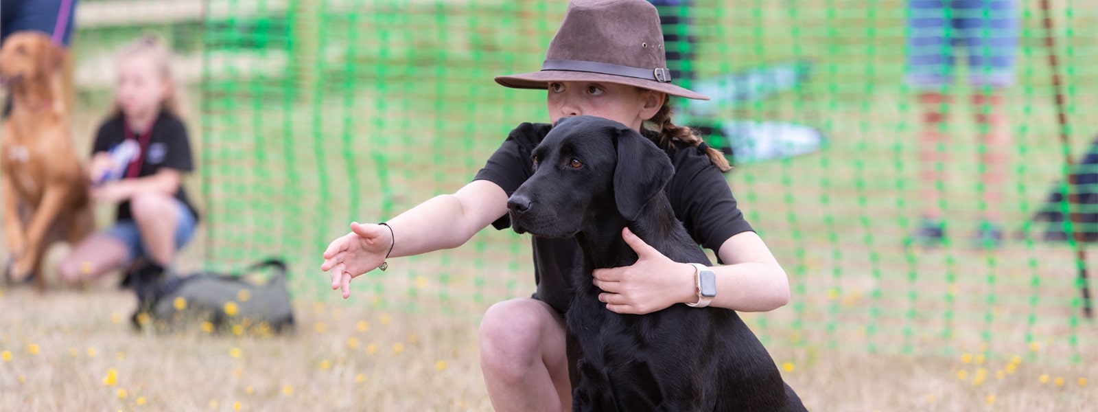 A young person with their black labrador