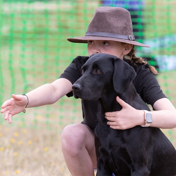 A young person with their black labrador
