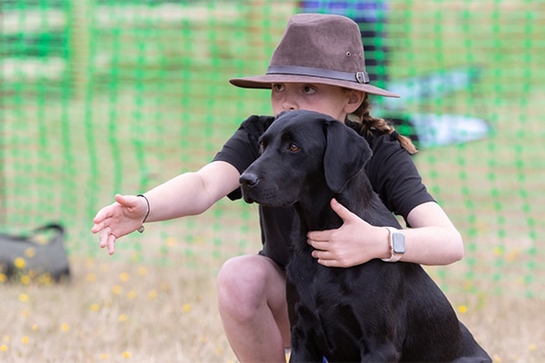 A young person with their black labrador