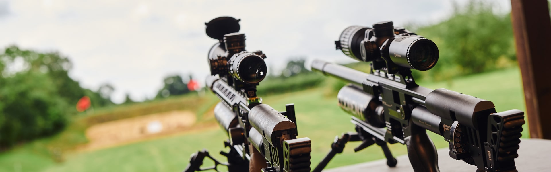 Two air rifles pointing out onto a target range