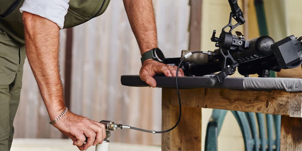 A person refilling the air in a rifle