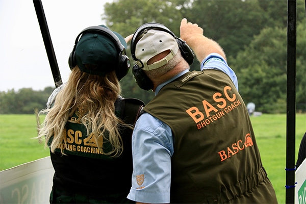 A coach pointing to the sky next to a student