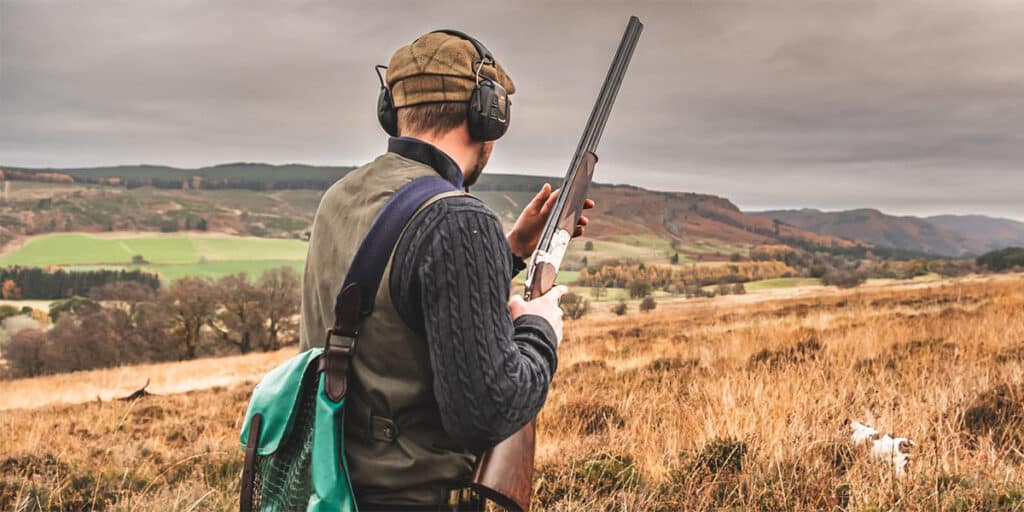 A game shooter holding a shotgun