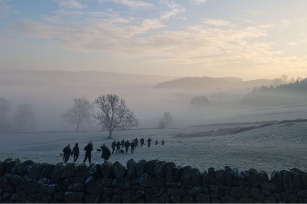 Game shooters walking through a frosty field
