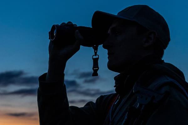 Night deer stalker looking through binoculars