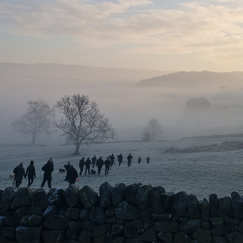 Game shooters walking through a frosty field