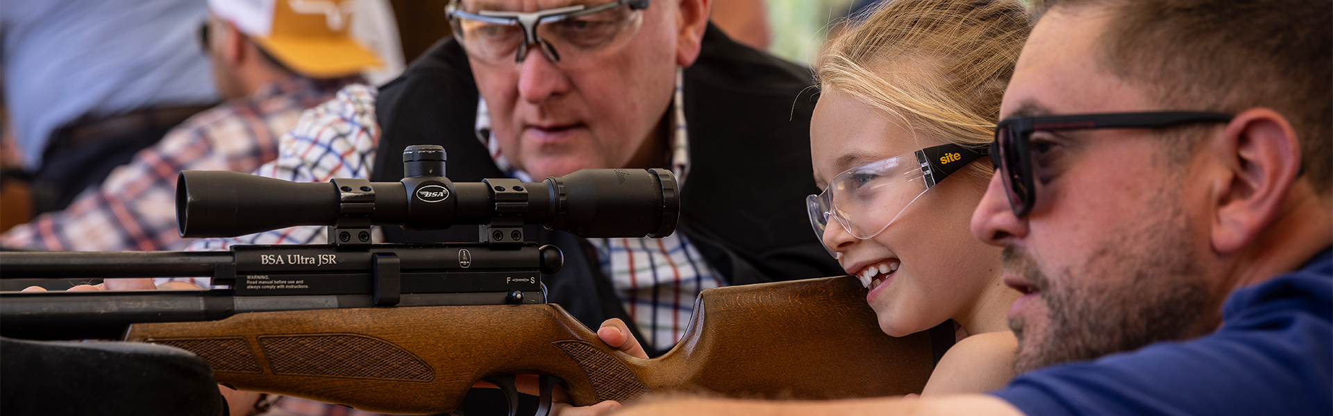 An air rifle coach teaching a child how to shoot an air rifle
