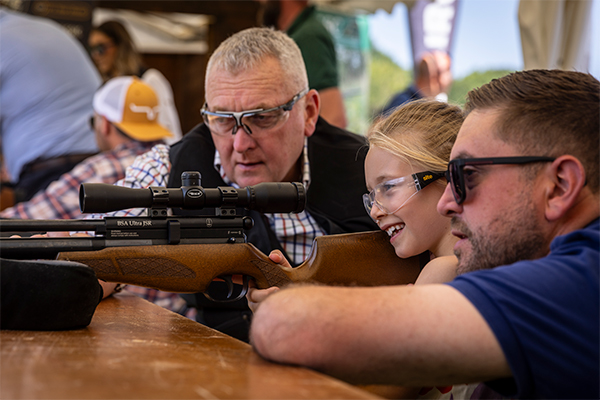 An air rifle coach teaching a child how to shoot an air rifle