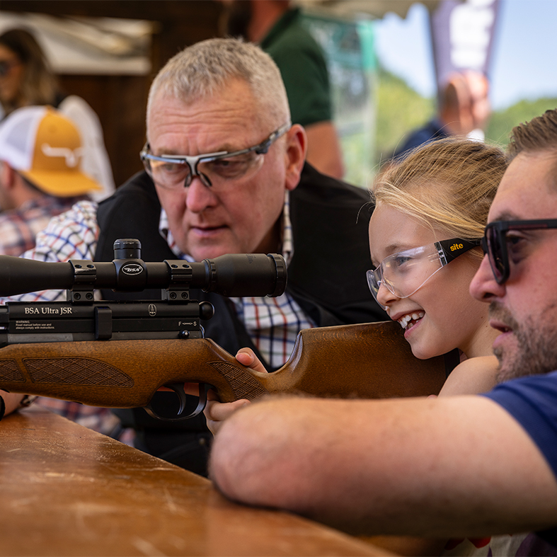 An air rifle coach teaching a child how to shoot an air rifle